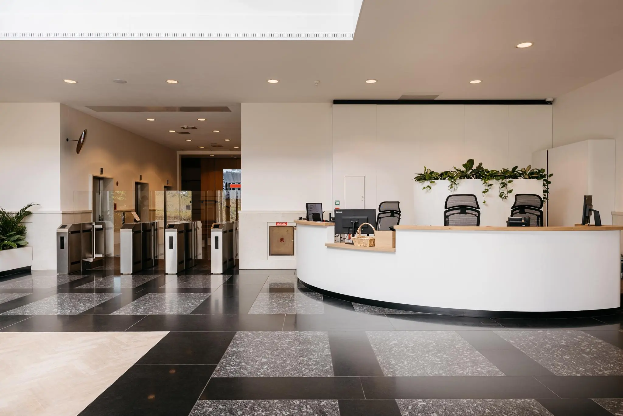 Moderne entreehal met een receptiebalie, toegangspoortjes en strakke zwart-witte vloer bij Fascinatio Boulevard.